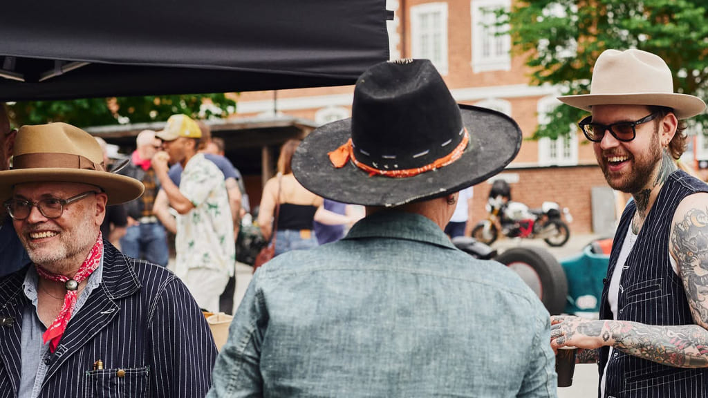 Stetson: A rugged cowboy, dressed in traditional attire including a Stetson hat, strolls alongside a majestic horse amidst the breathtaking mountainous landscape.